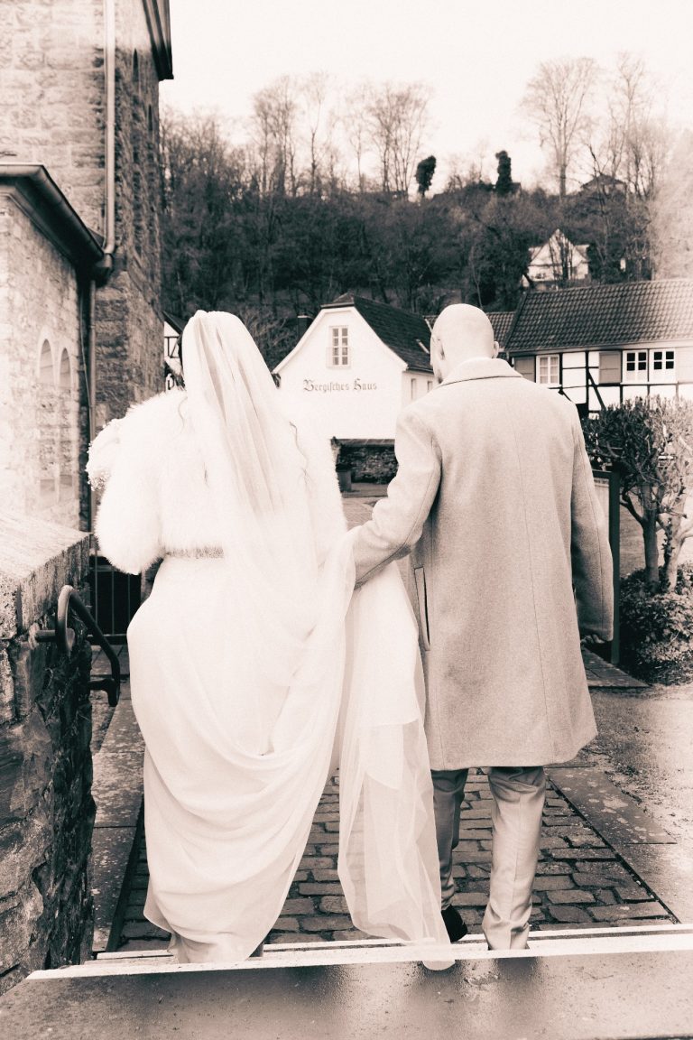 Brautpaar geht Hand in Hand, auf einem Weg in eine malerische Umgebung.