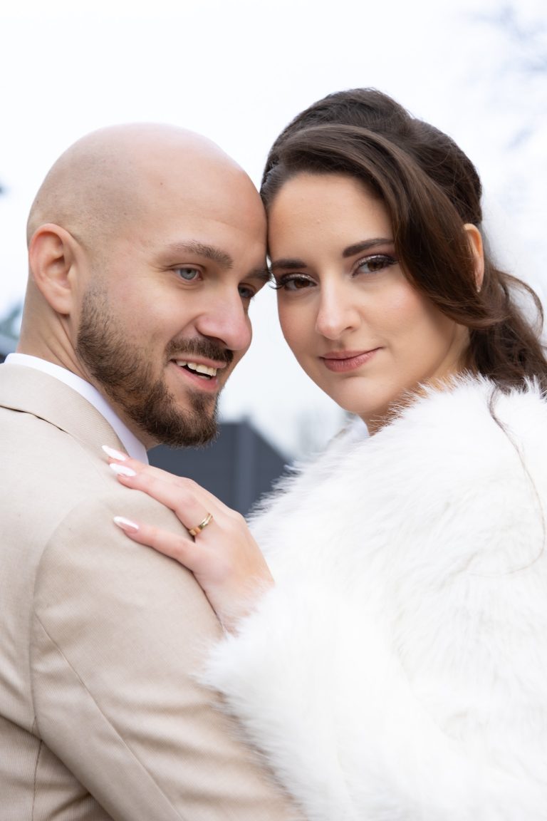 Ein Brautpaar posiert liebevoll, umgeben von winterlicher Landschaft.