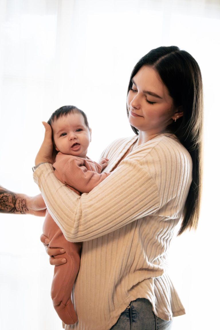 Eine Frau hält ein Baby in den Armen, beide schauen in die Kamera.