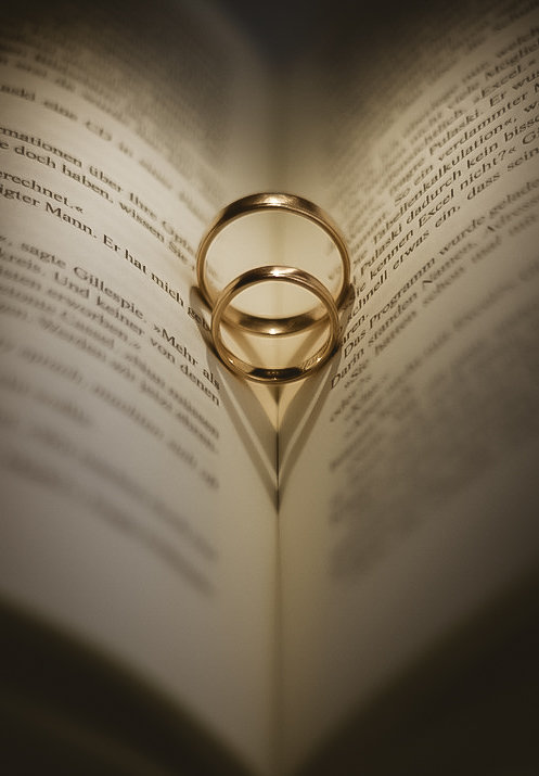 Zwei goldene Hochzeitsringe liegen auf einer offenen Buchseite.