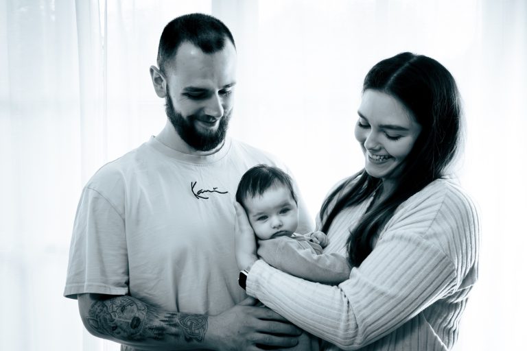 Familie mit einem Baby, das von den Eltern liebevoll gehalten wird.