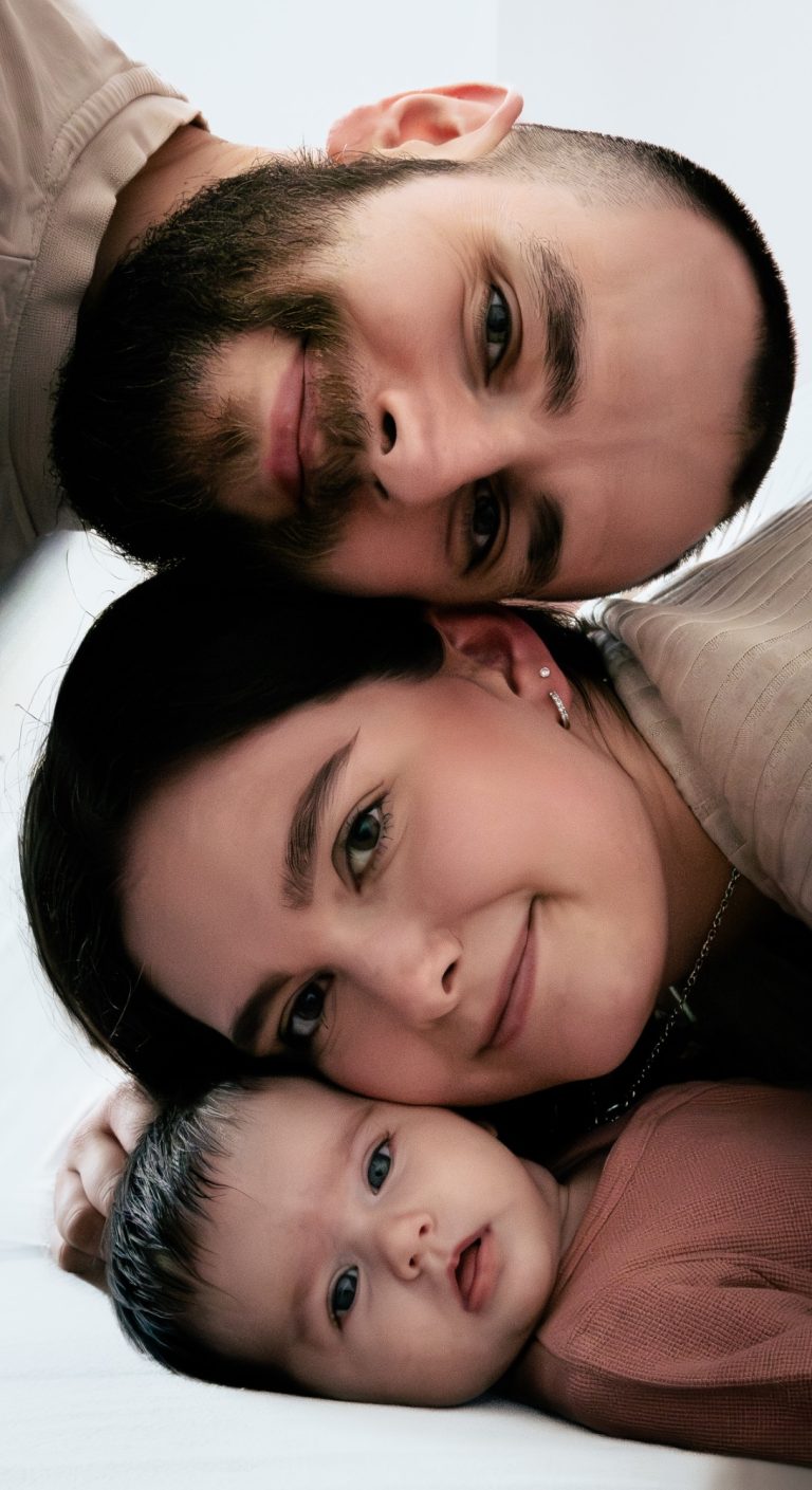 Eine Familie besteht aus einem Mann, einer Frau und einem Baby in einer engen Umarmung.